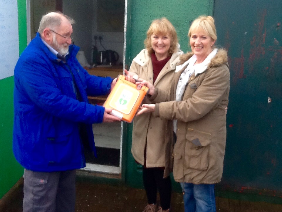 Allotments chairman Nigel being presented with defibrillator by Doreen and Peggy who organised the race night that raised the required funds.